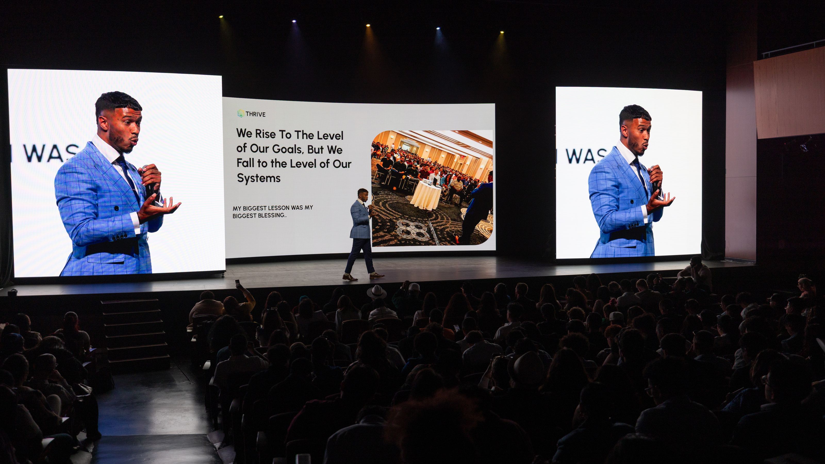 Neno on stage in a full arena, his slides on screens either side