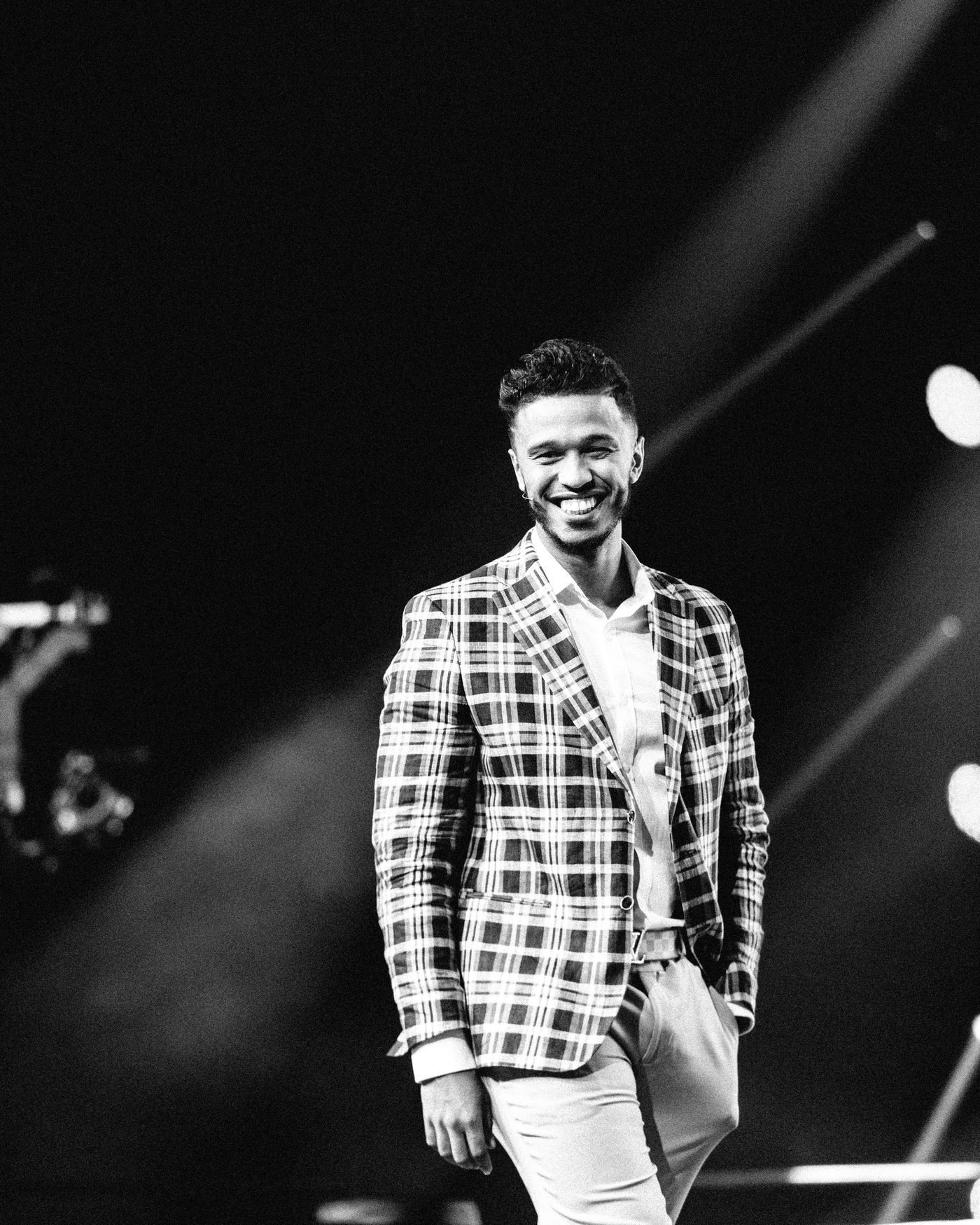 Neno Torres on stage, smiling under the lights, black and white