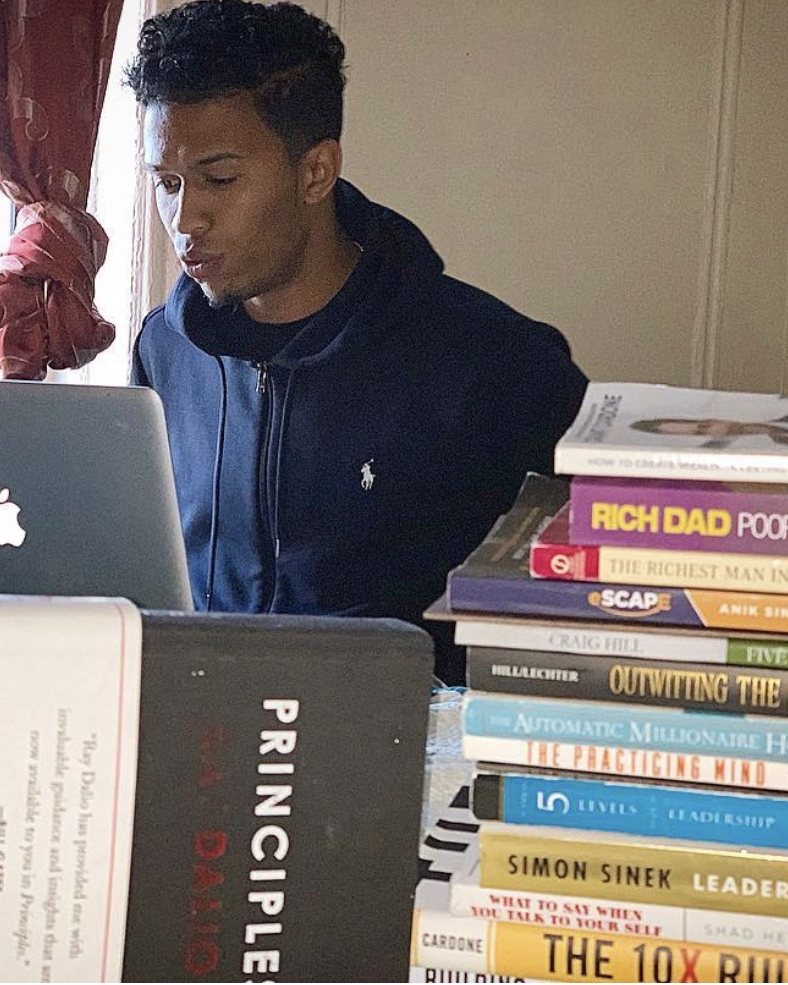Neno at his laptop beside a stack of books
